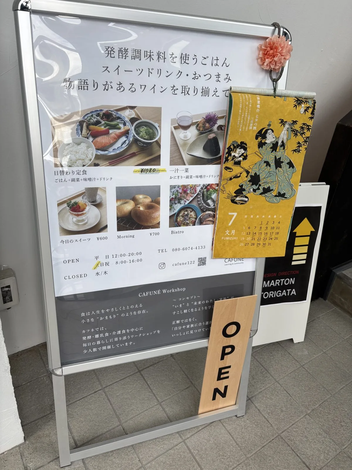 CAFUNE'の1階入口に置かれたOPEN看板。メニュー写真と営業時間、七夕の浮世絵カレンダー付き