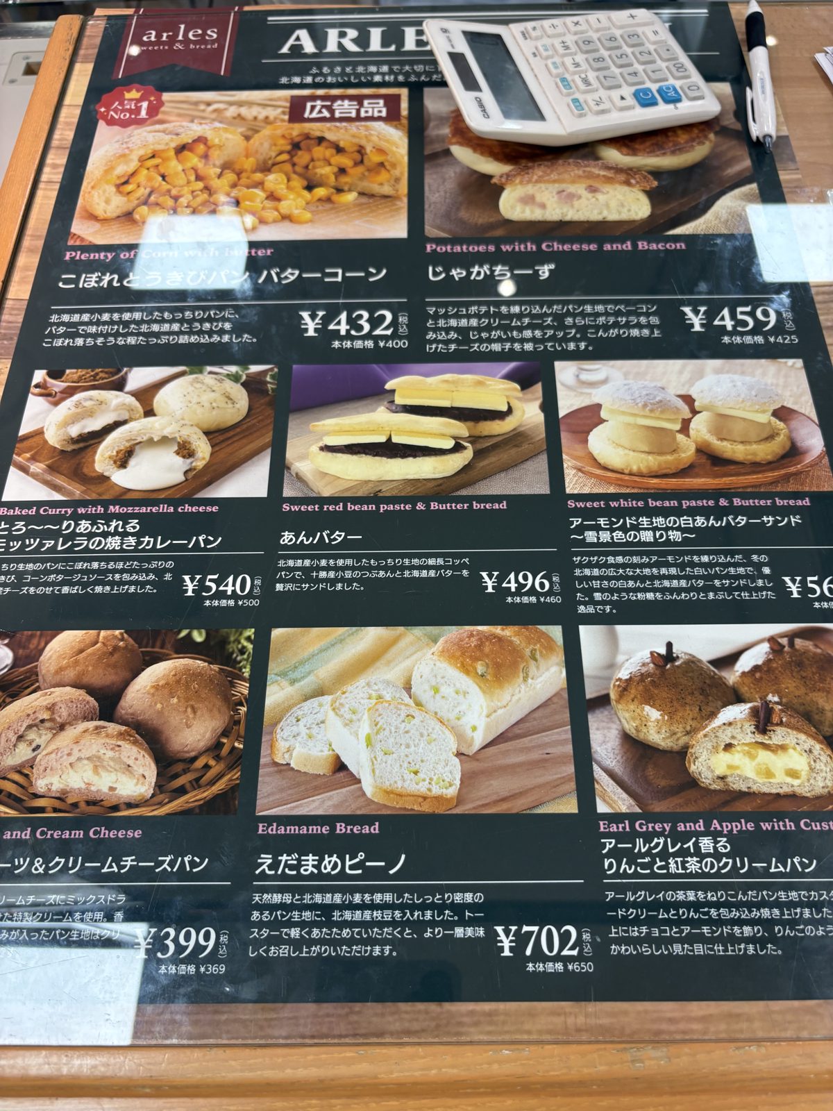 イルマットーネ・アルルのメニュー看板。こぼれとうきびパン432円、焼きカレーパン540円など