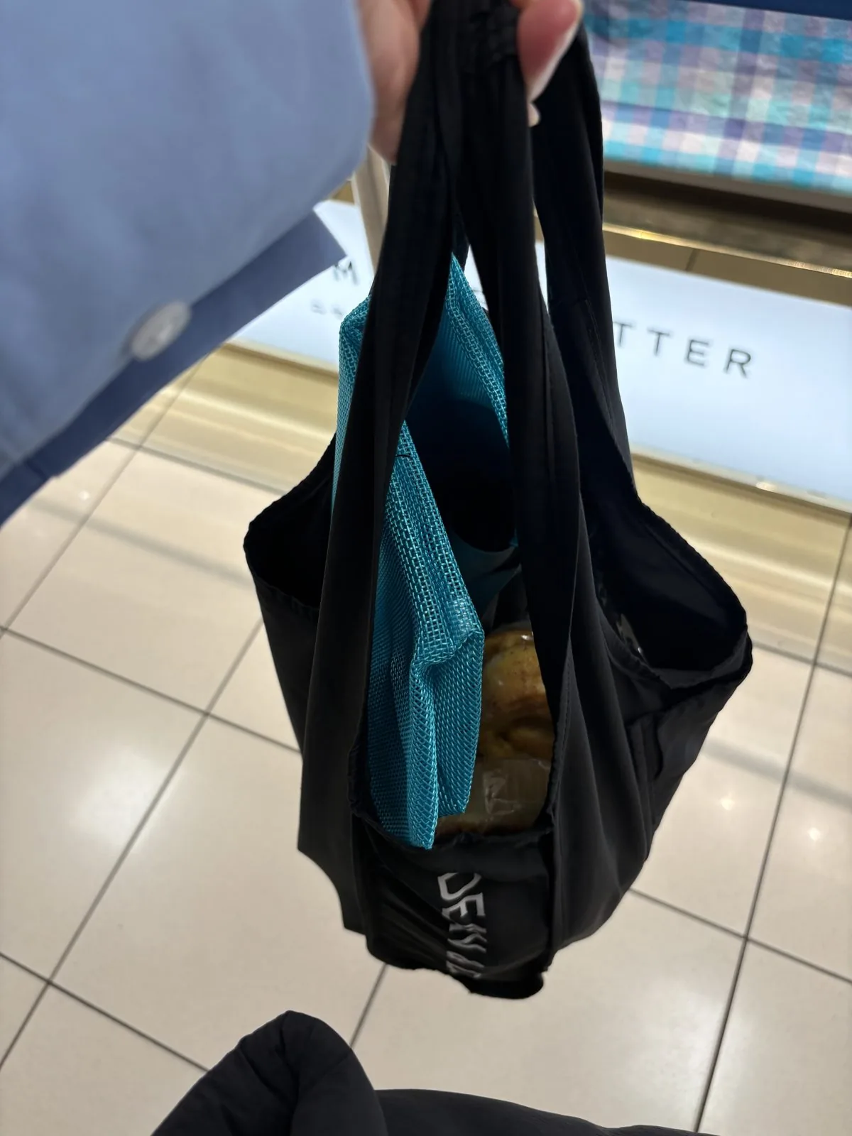 黒いD&Dショッピングバッグの中に、新しく買ったターコイズのメッシュトートとシナモンロールが入っている