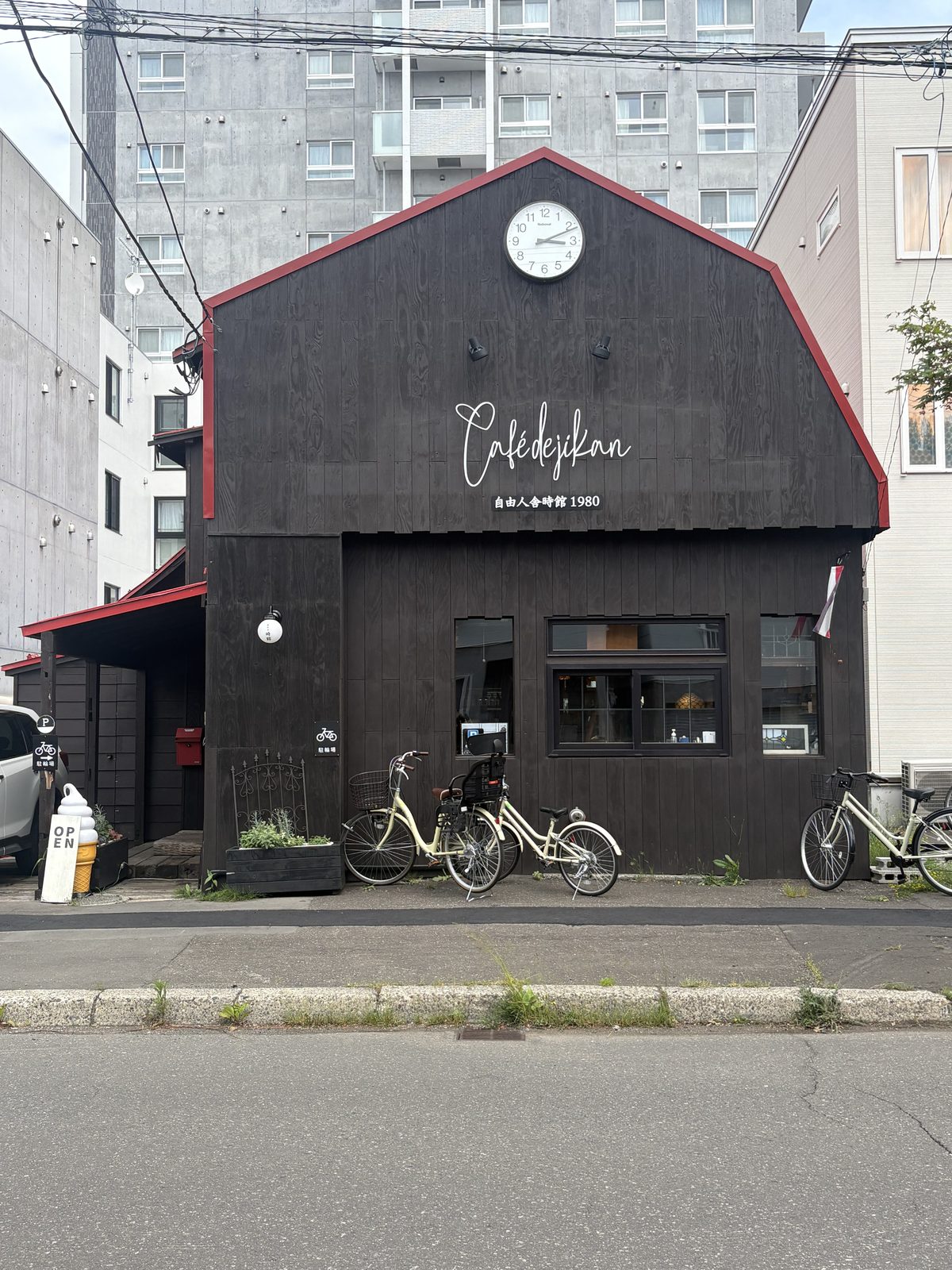 札幌・北区のCAFE de JIKAN(カフェ時館)の外観。古い馬小屋をリノベした黒い三角屋根の建物に時計