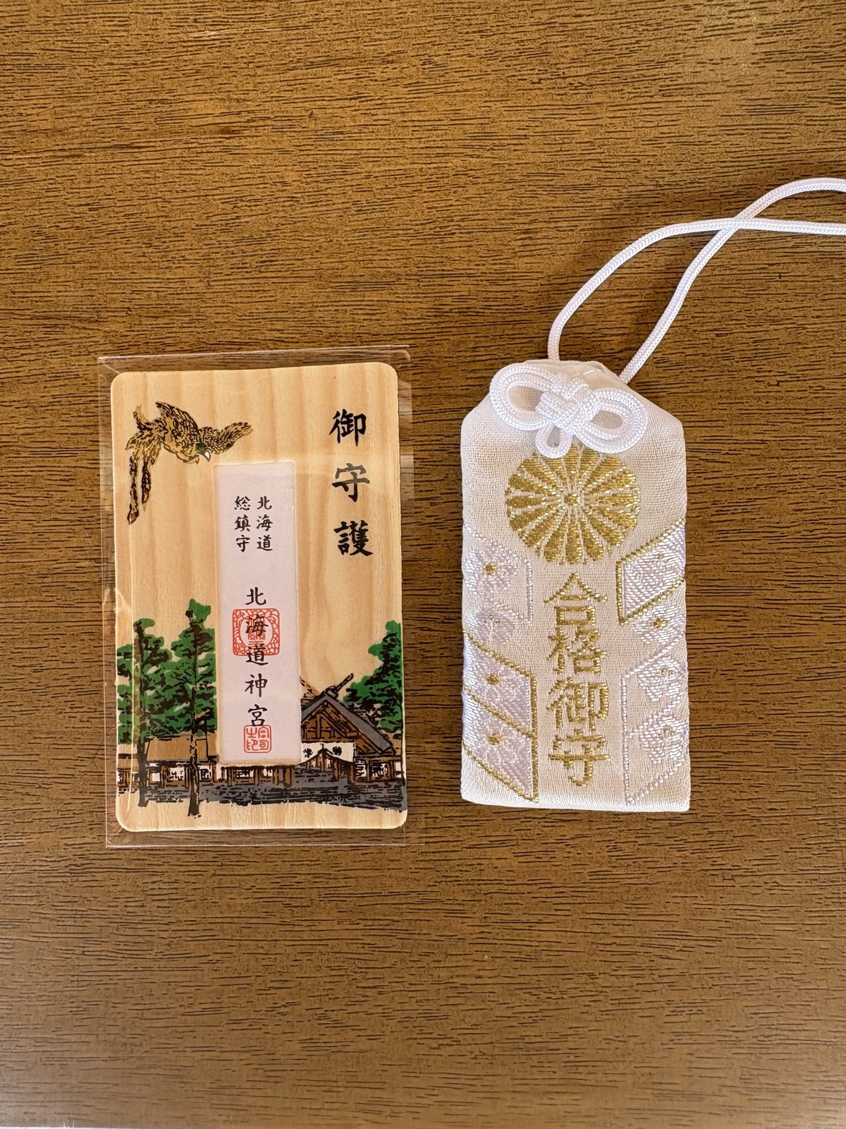 北海道神宮で購入したお守り。木の板の御守護と金色の菊紋のお守り