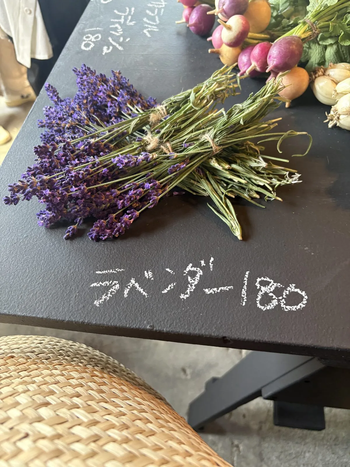 黒いテーブルに置かれたラベンダーの束。チョークでラベンダー180円と書かれている
