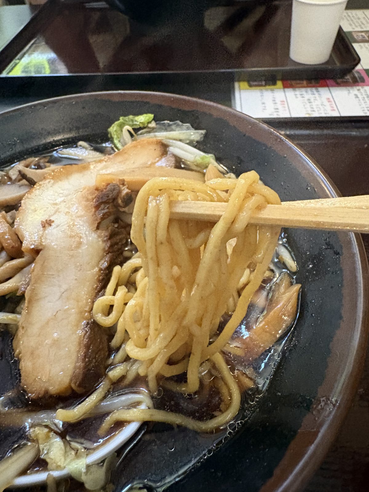きのこ醤油ラーメンのちぢれ麺を箸で持ち上げたところ