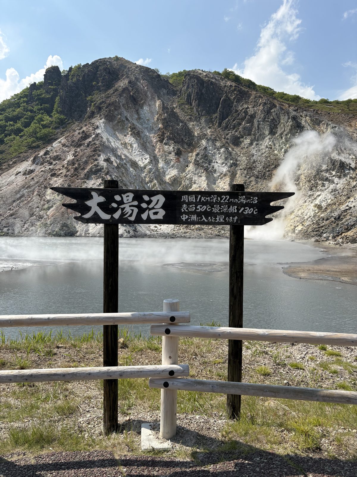 登別の大湯沼。灰色がかった湯面から湯けむりが立ちのぼる大きな沼と「大湯沼」の看板