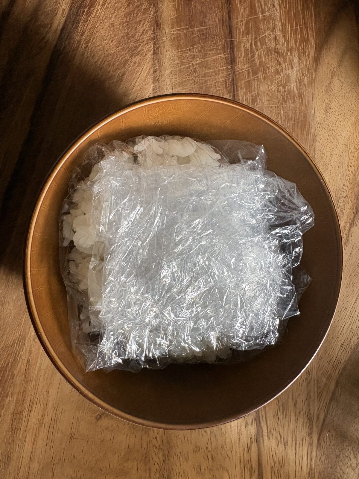 ラップの四隅を持ち上げておにぎりを包んでいるところ