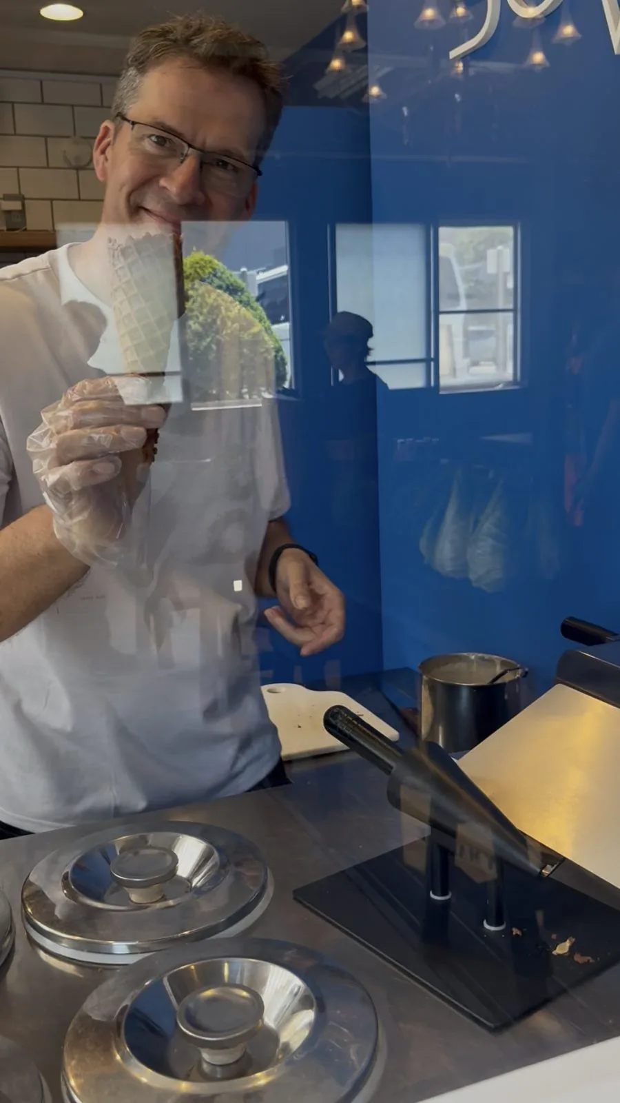 ガラス越しに、焼きたてのワッフル生地を見せて微笑んでくれる店主さん
