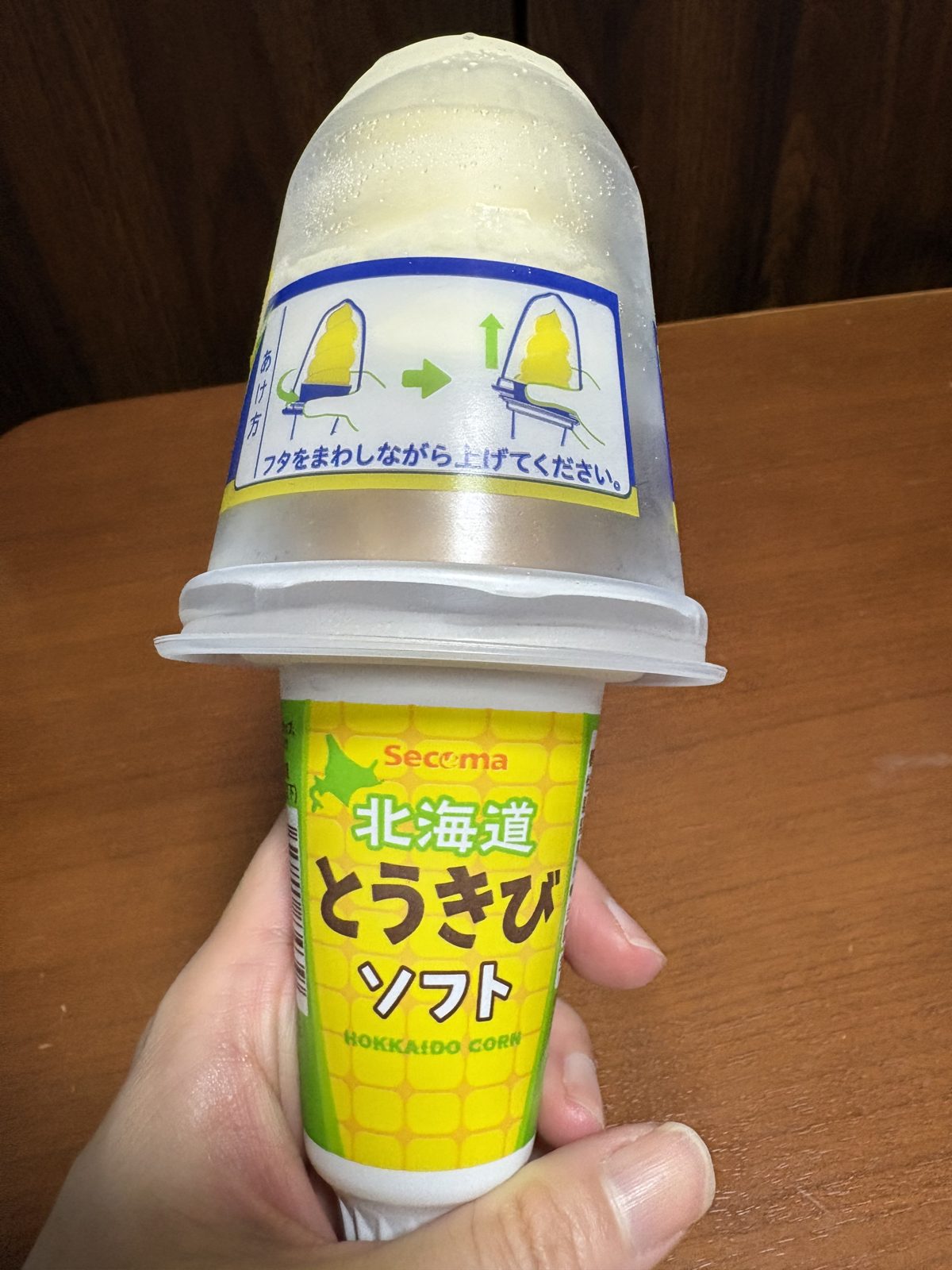 北海道とうきびソフトのカップ。黄色いパッケージに「あけ方」の説明とコーンのイラスト