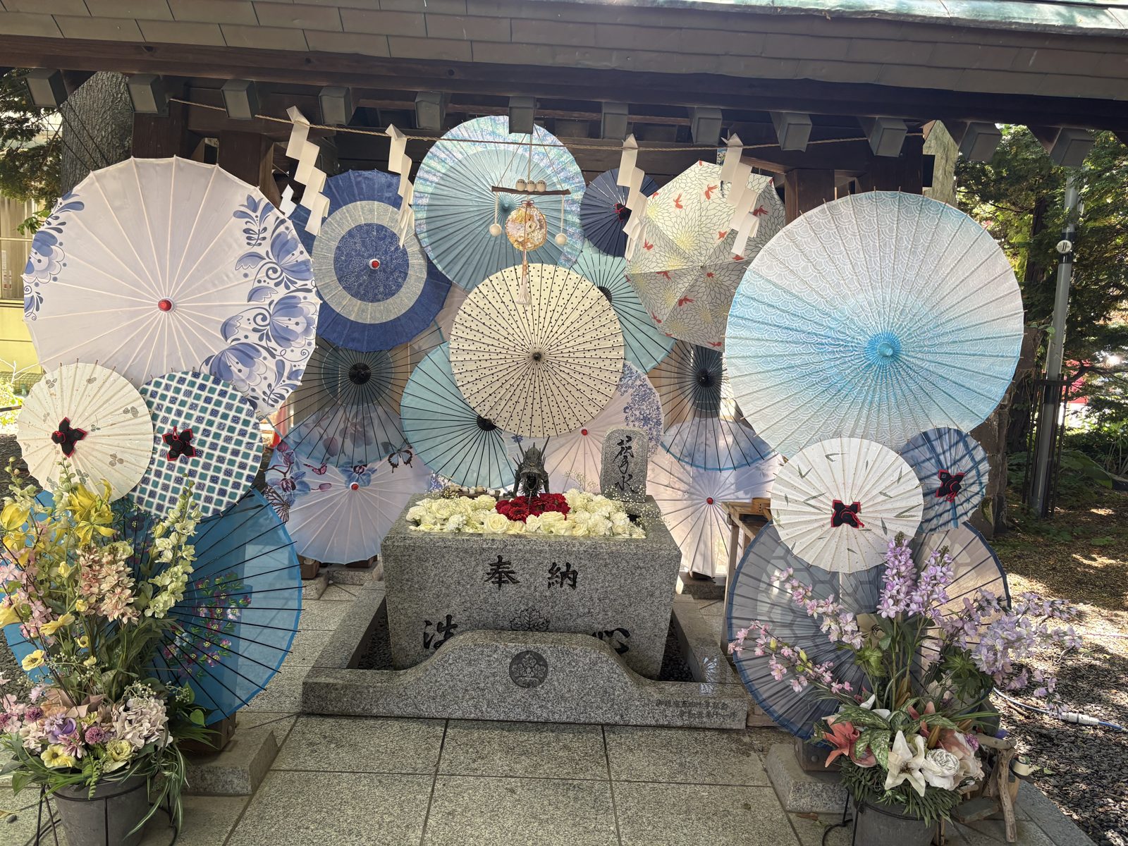 札幌諏訪神社の和傘と花で飾られた一角。奉納の石の周りに和傘とお花