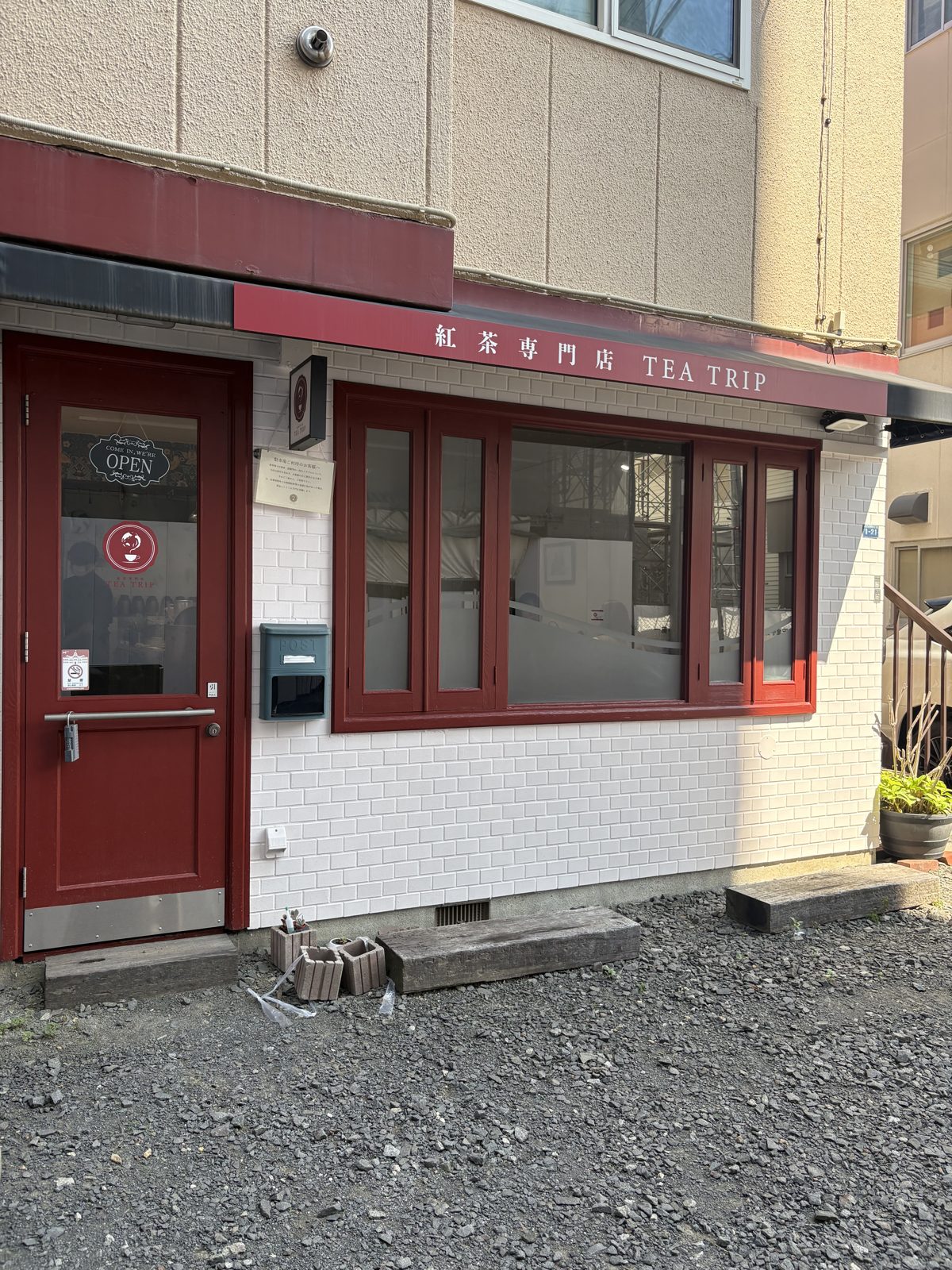 紅茶専門店TEA TRIPの外観。赤い扉に紅茶専門店 TEA TRIPの看板