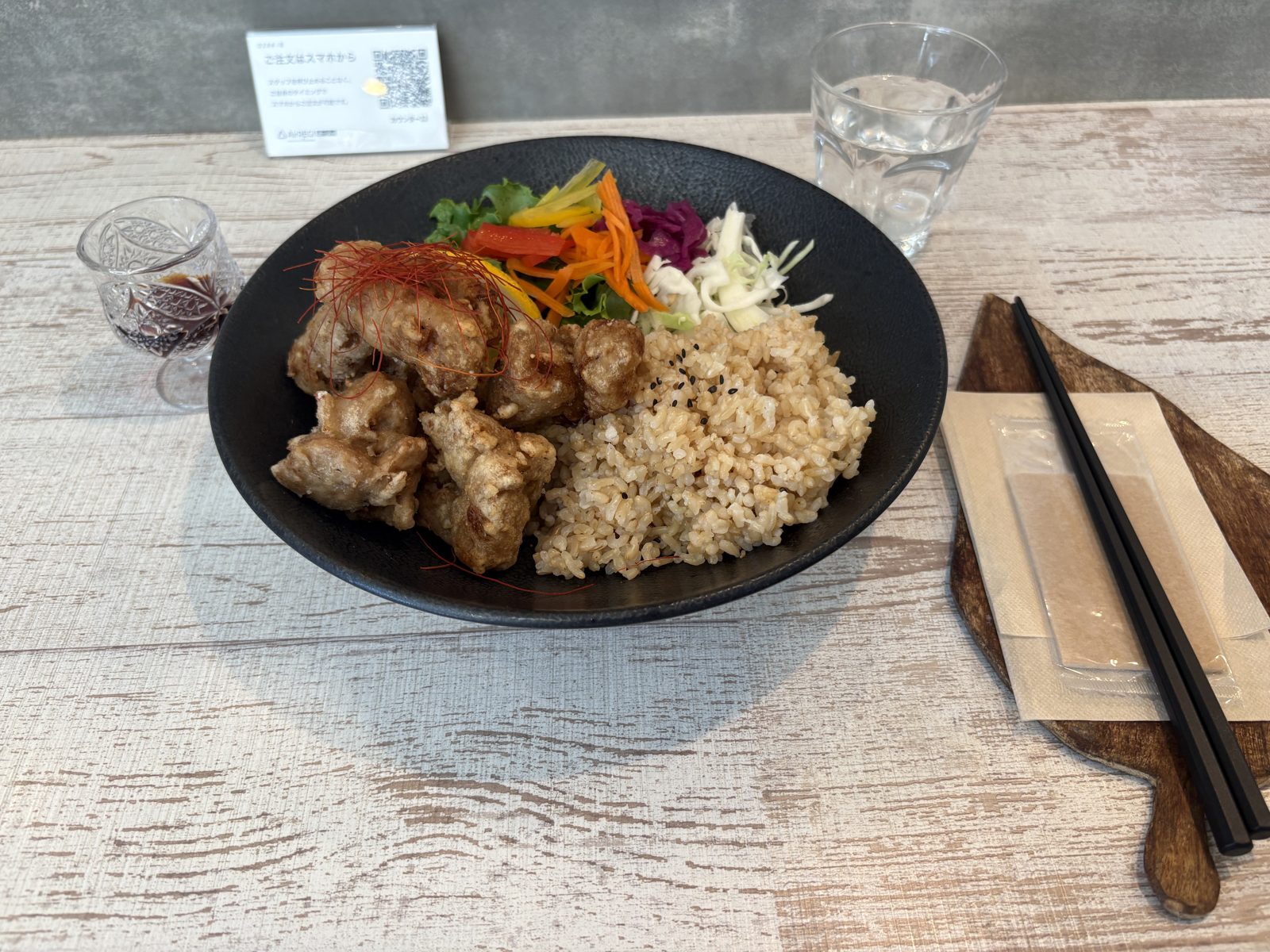 運ばれてきたザンタレBOWL。黒い器にヴィーガンザンギと玄米ごはん、彩り野菜