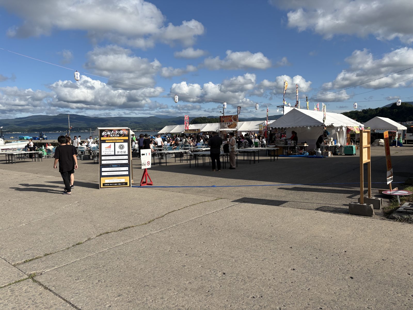 余市町の北海ソーラン祭り会場。テントが並び、青空と海が広がっている