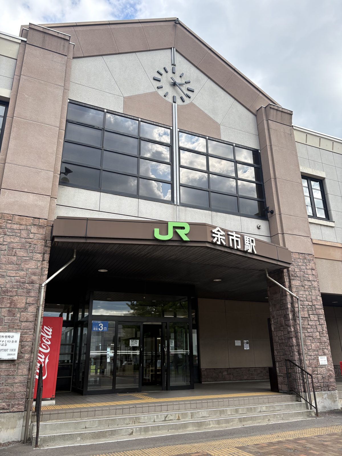 JR函館本線・余市駅の駅舎。三角屋根に時計、JRの緑のロゴと「余市駅」の文字