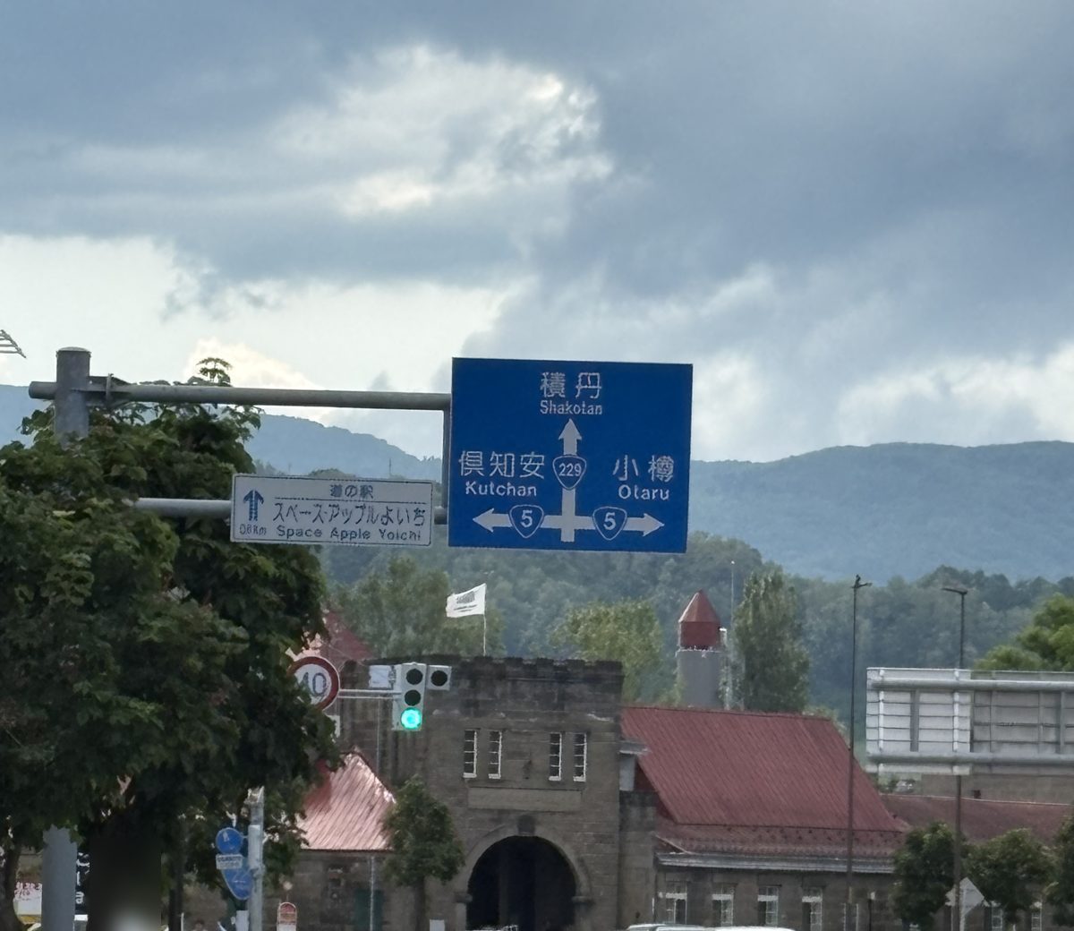 余市の街並み。積丹・倶知安・小樽方面の道路標識と、赤い屋根の歴史的な石造りの建物