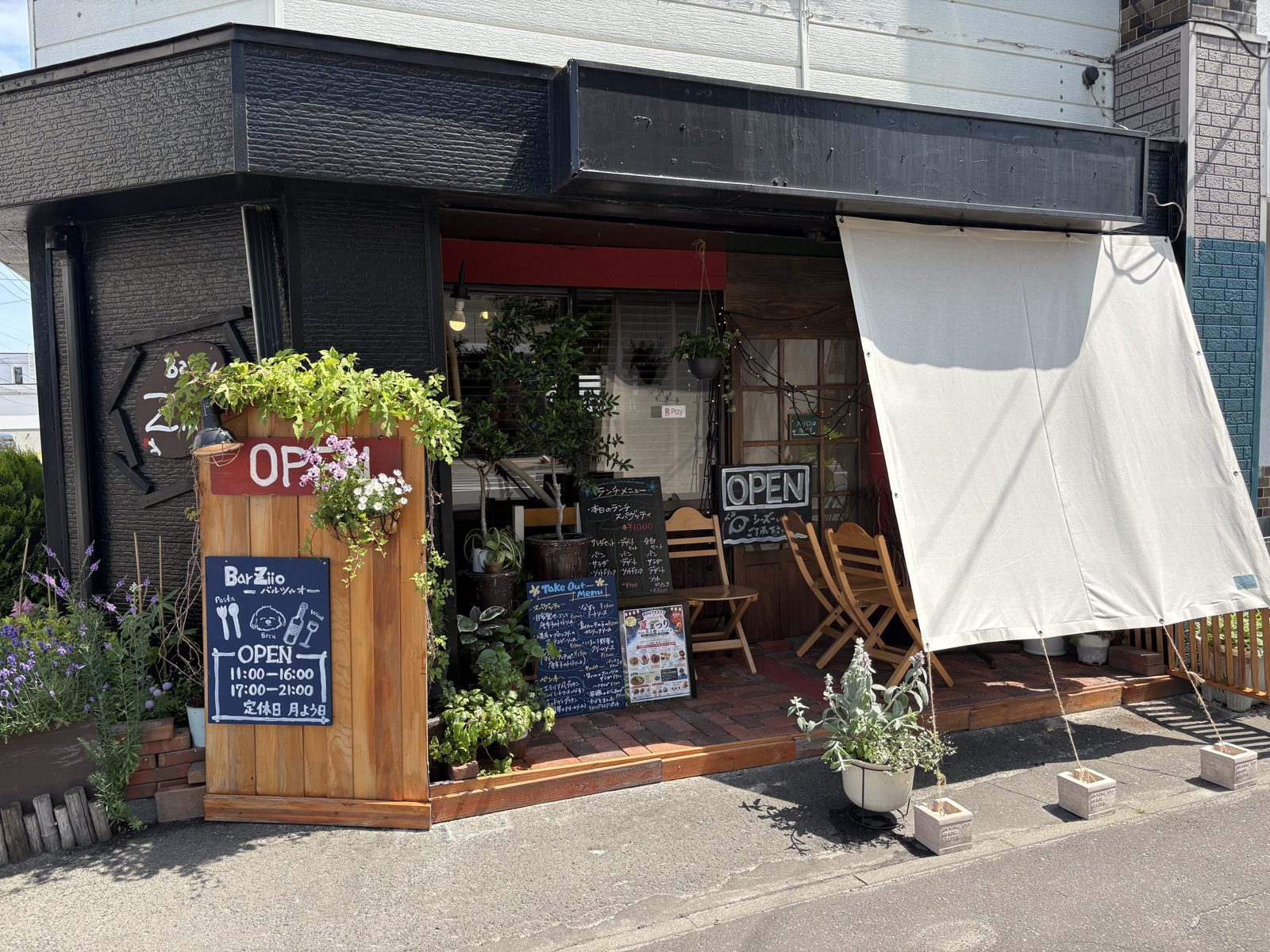 Bar Ziioの外観全景。黒い建物に白いテントと緑