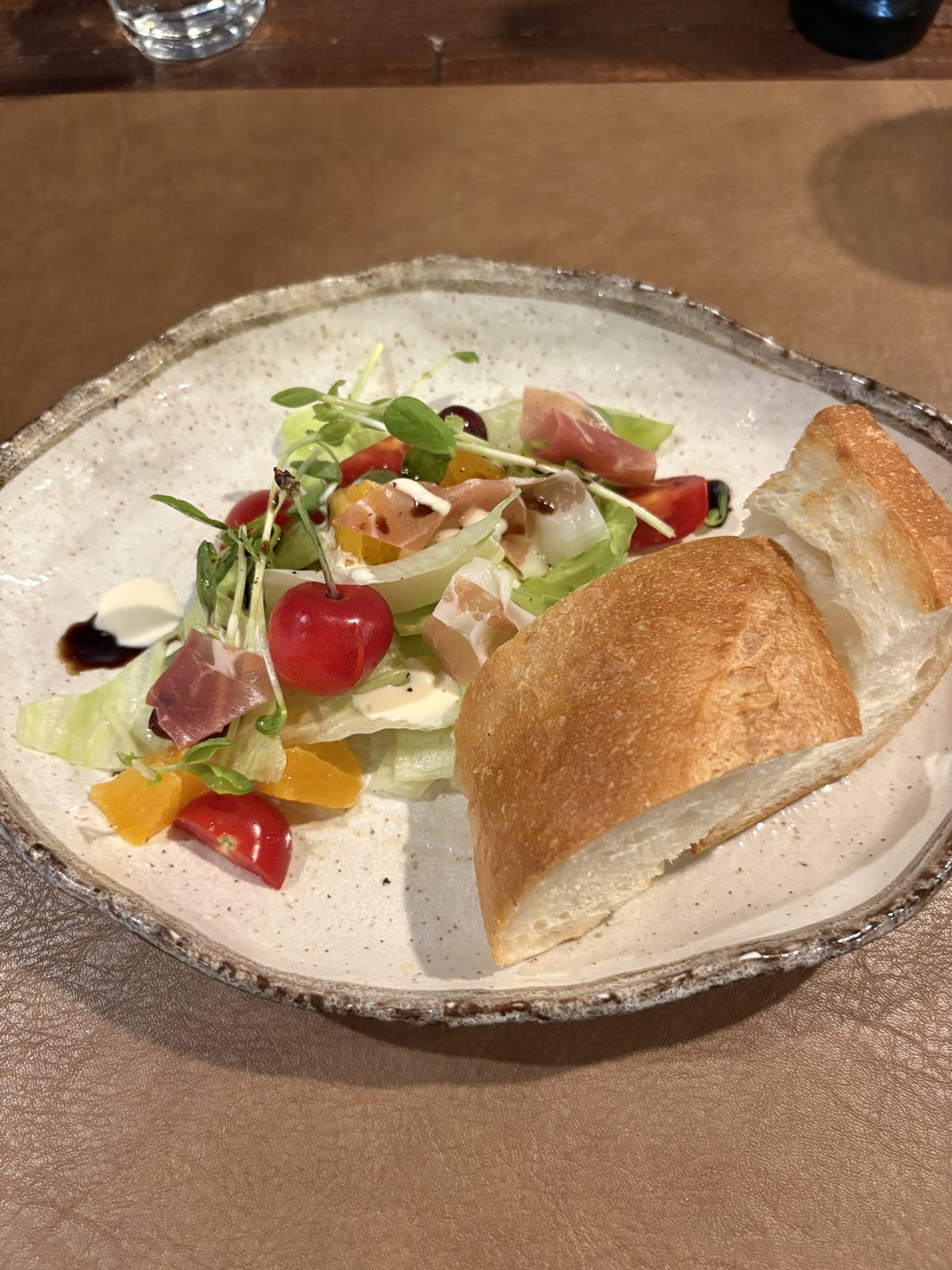 フルーツと生ハムのサラダとパン。さくらんぼ、みかん、ぶどう、ミニトマト入り